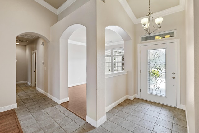 entryway with crown molding, light tile patterned floors, a notable chandelier, and high vaulted ceiling