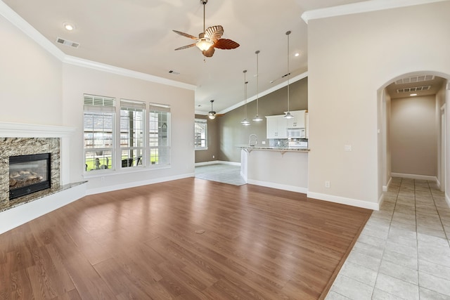 unfurnished living room with crown molding, a premium fireplace, and ceiling fan