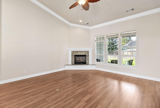 unfurnished living room with ceiling fan, ornamental molding, a high end fireplace, and wood-type flooring