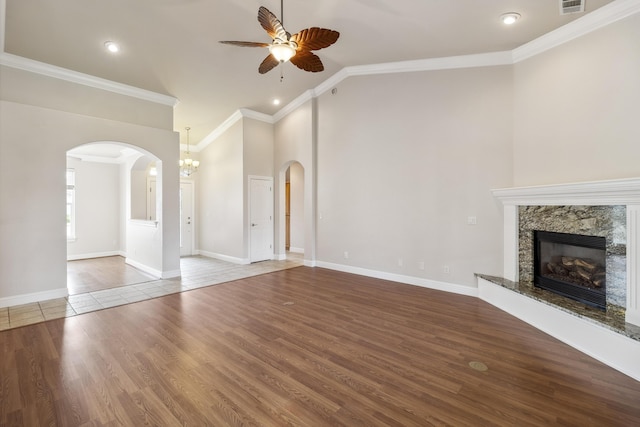 unfurnished living room featuring a premium fireplace, wood-type flooring, ceiling fan, and ornamental molding