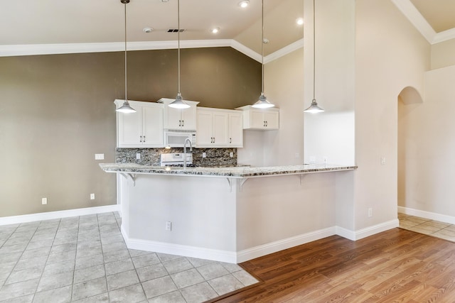 kitchen with pendant lighting, light stone counters, white appliances, and white cabinets