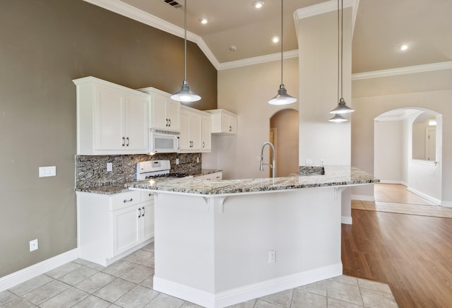 kitchen featuring stone counters, stove, a kitchen bar, and white cabinets