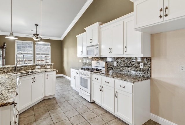 kitchen with sink, white appliances, hanging light fixtures, white cabinets, and stone countertops