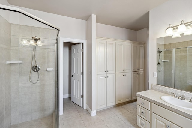 bathroom with a shower with door, vanity, and tile patterned floors