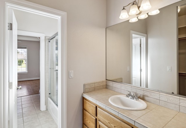 bathroom featuring tile patterned flooring, vanity, a notable chandelier, and shower / bath combination with glass door