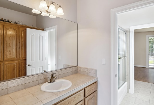 bathroom with an inviting chandelier, enclosed tub / shower combo, vanity, and tile patterned floors