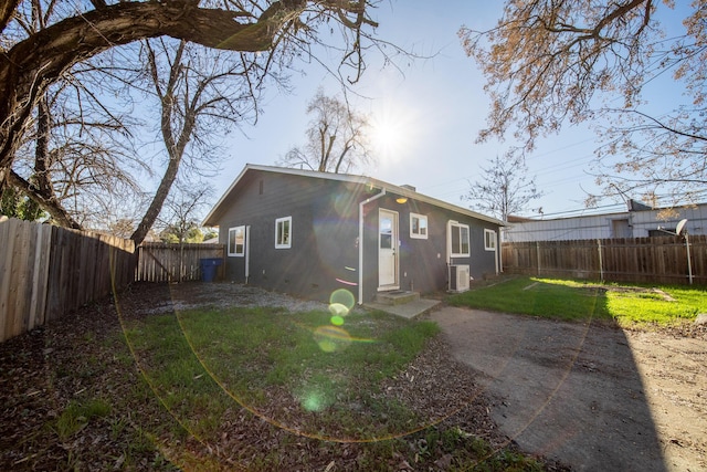 rear view of property with a lawn and central air condition unit