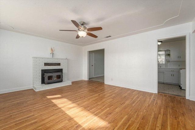 unfurnished living room featuring ceiling fan, wood-type flooring, and a fireplace