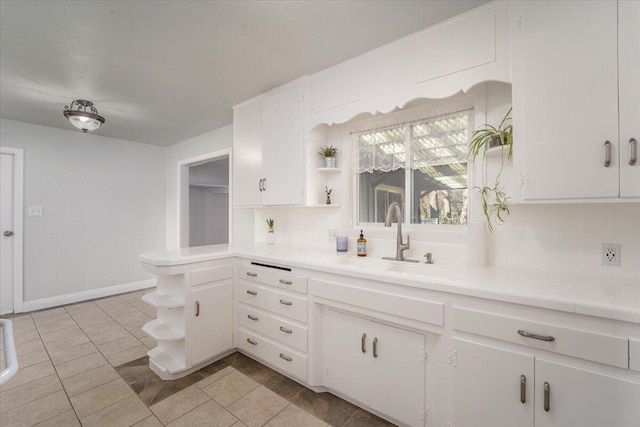 kitchen with sink, light tile patterned floors, and white cabinets