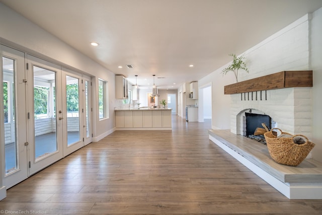 unfurnished living room with hardwood / wood-style flooring, a brick fireplace, and french doors