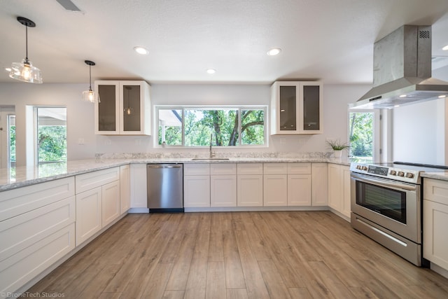 kitchen with sink, white cabinetry, island range hood, stainless steel appliances, and light stone countertops