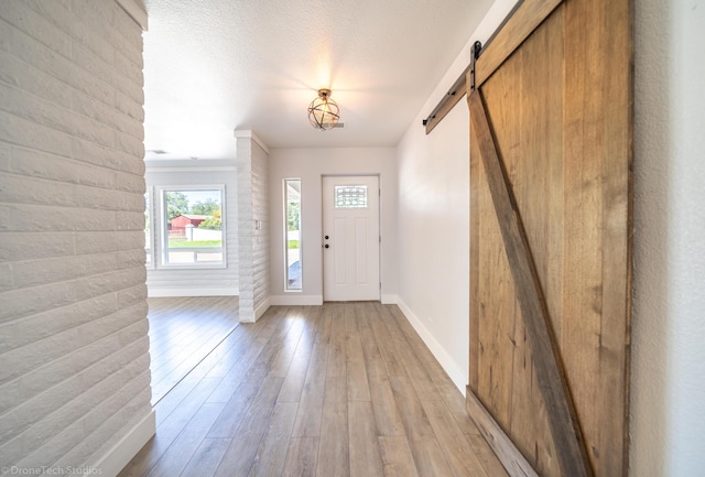 entryway featuring a barn door, light hardwood / wood-style flooring, and a textured ceiling