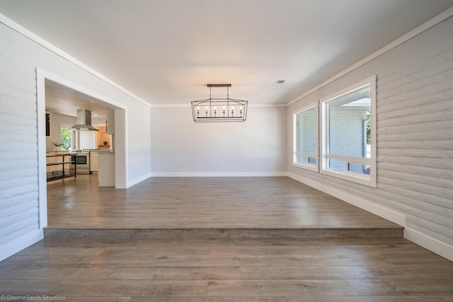 empty room featuring ornamental molding, wood-type flooring, and a notable chandelier