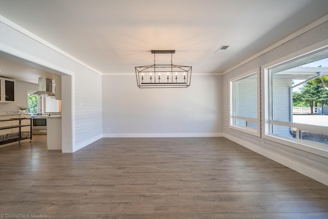 dining room with an inviting chandelier, hardwood / wood-style flooring, plenty of natural light, and ornamental molding