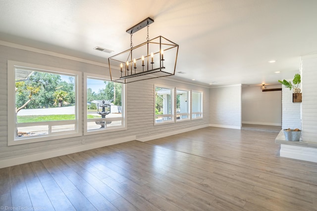 unfurnished living room with plenty of natural light, ornamental molding, and wood-type flooring