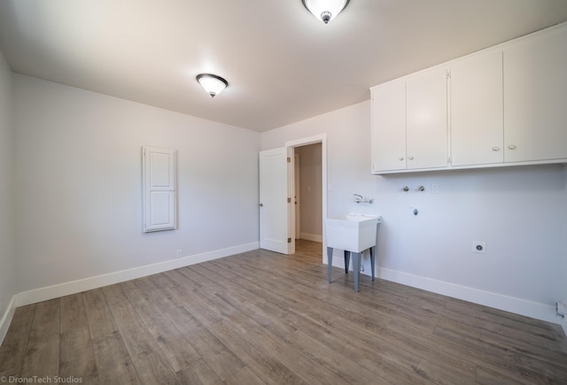 clothes washing area with cabinets, hookup for a washing machine, hookup for an electric dryer, and light hardwood / wood-style flooring