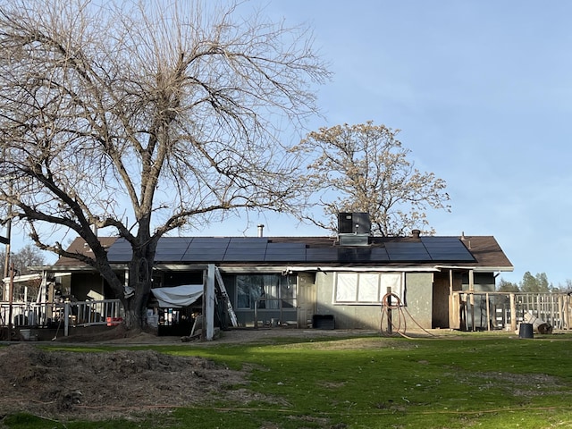 rear view of property featuring central AC, a yard, and solar panels