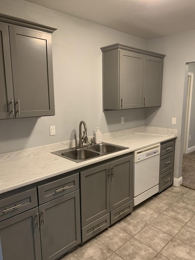 kitchen featuring white dishwasher, sink, light tile patterned floors, and gray cabinetry