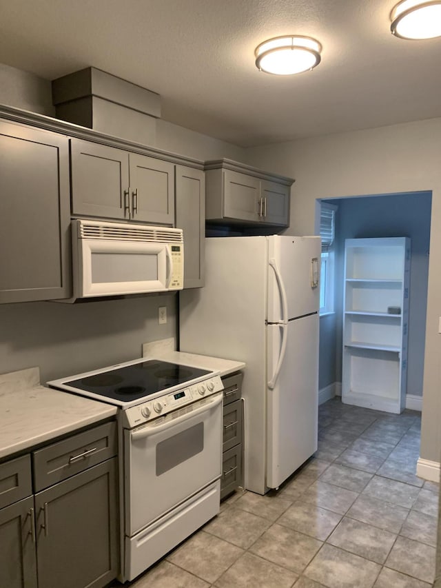 kitchen with gray cabinetry, white appliances, and a textured ceiling