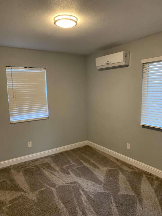 carpeted spare room featuring a wall mounted AC and a textured ceiling