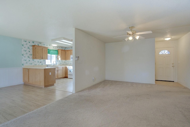 unfurnished living room with light colored carpet and ceiling fan