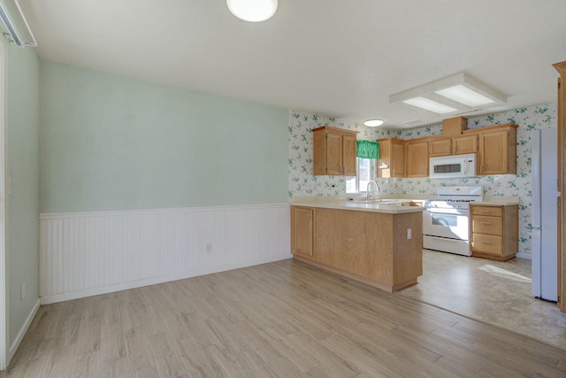 kitchen featuring sink, white appliances, light hardwood / wood-style floors, and kitchen peninsula