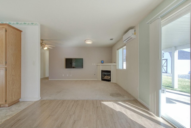 unfurnished living room with ceiling fan, a wall mounted air conditioner, and light hardwood / wood-style flooring