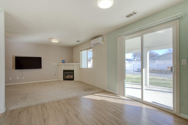 unfurnished living room featuring a wall mounted AC and light wood-type flooring