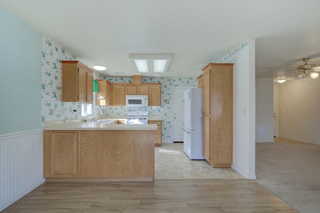 kitchen with light brown cabinetry, sink, kitchen peninsula, white appliances, and light hardwood / wood-style flooring