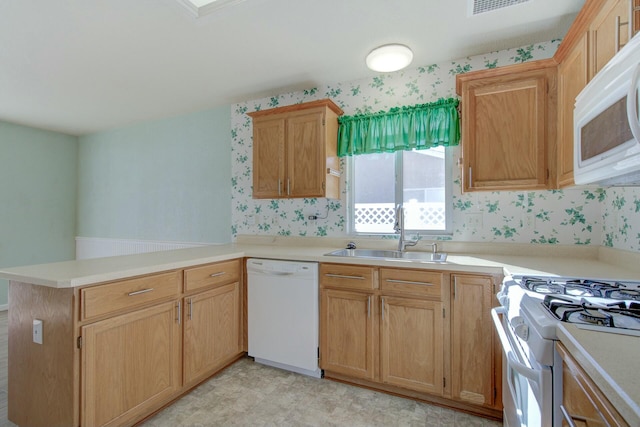 kitchen with white appliances, kitchen peninsula, and sink