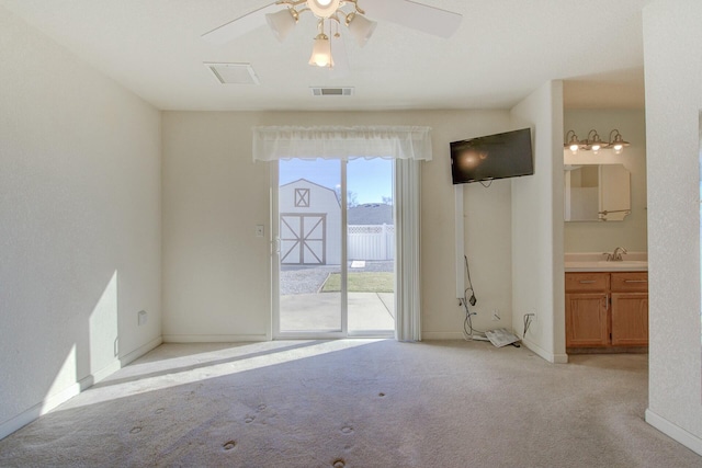 spare room featuring ceiling fan, sink, and light carpet