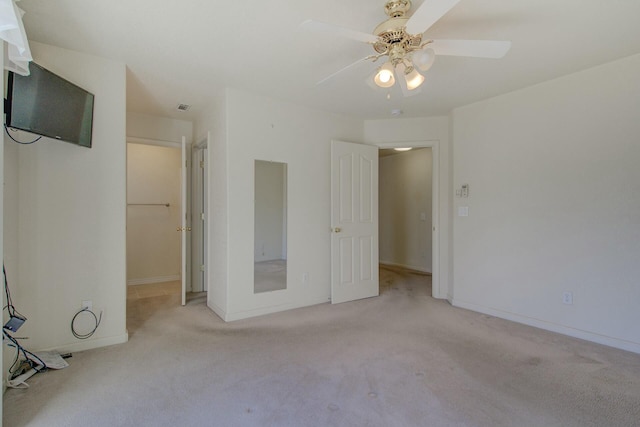 unfurnished bedroom featuring a spacious closet, light carpet, ceiling fan, and a closet