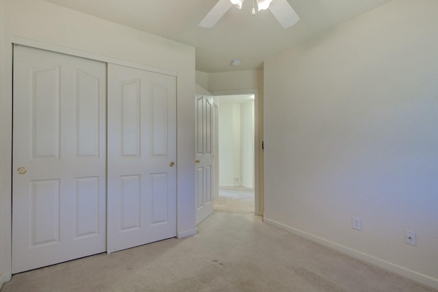 unfurnished bedroom with light colored carpet, a closet, and ceiling fan