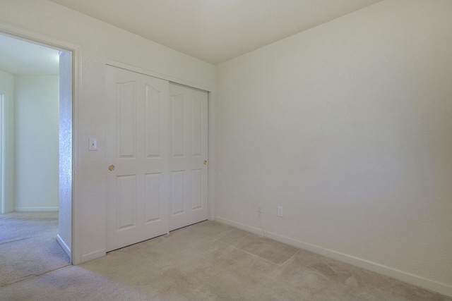 unfurnished bedroom featuring light carpet and a closet