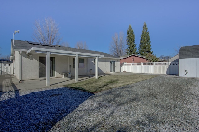 rear view of house featuring a yard, a patio area, and solar panels