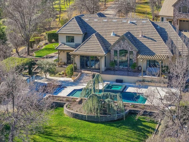 back of house featuring an in ground hot tub, a patio, and a lawn