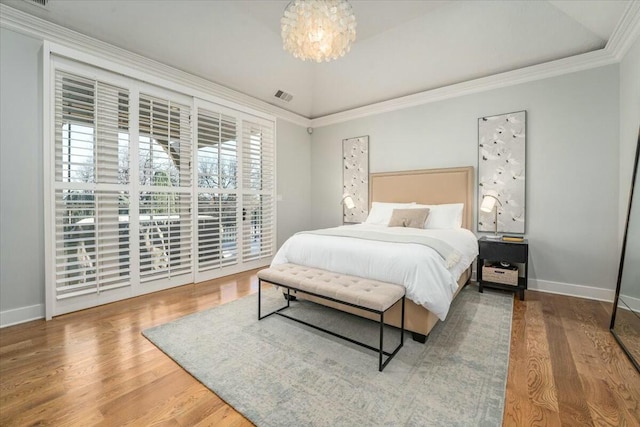 bedroom featuring crown molding, lofted ceiling, wood-type flooring, and a tray ceiling