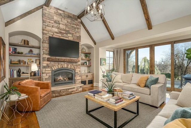 living room featuring hardwood / wood-style floors, a stone fireplace, a notable chandelier, and beamed ceiling