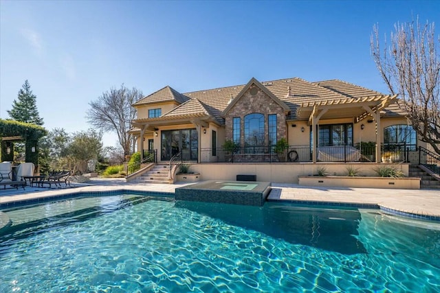 rear view of house with a swimming pool with hot tub and a patio