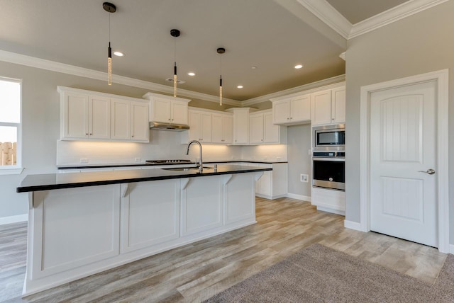 kitchen featuring pendant lighting, white cabinetry, an island with sink, sink, and stainless steel appliances