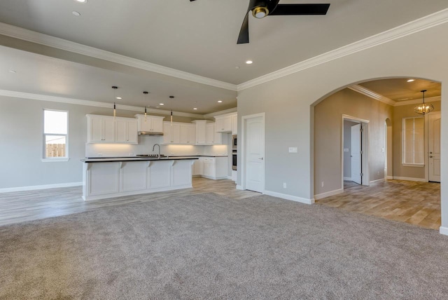 kitchen with decorative light fixtures, an island with sink, and white cabinets