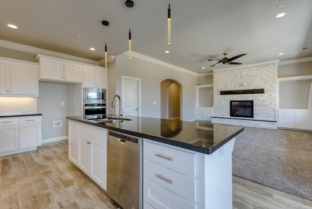 kitchen with stainless steel appliances, sink, a center island with sink, and white cabinets