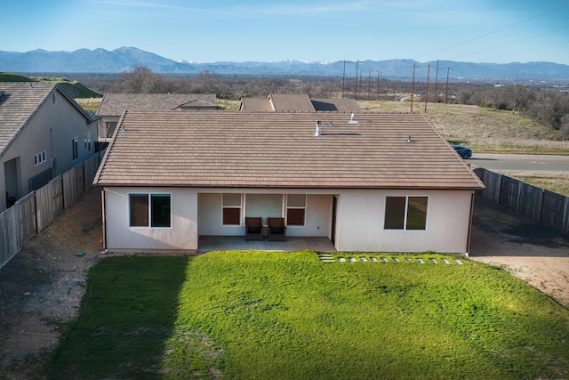 back of house with a mountain view, a yard, and a patio area