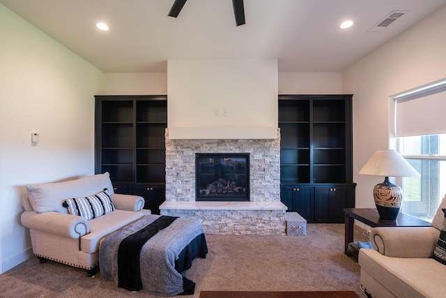 carpeted living room with ceiling fan and a fireplace