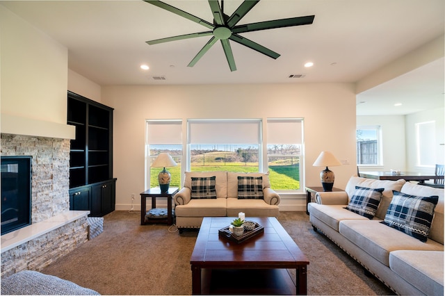 living room with ceiling fan, dark carpet, and a fireplace