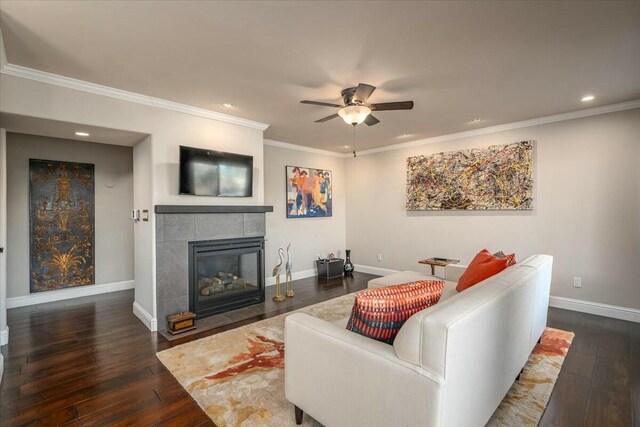 living room with crown molding, a fireplace, dark hardwood / wood-style floors, and ceiling fan