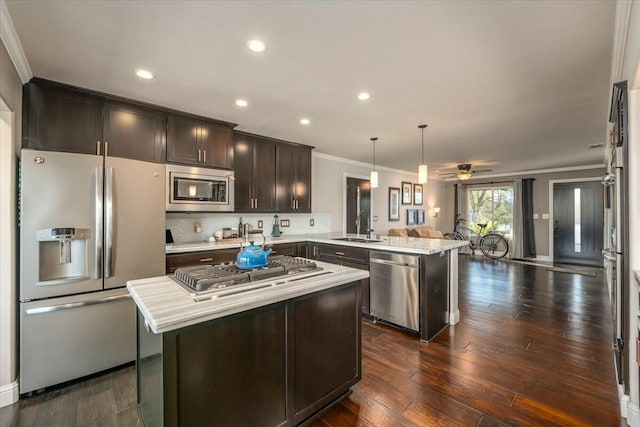 kitchen featuring dark brown cabinetry, sink, hanging light fixtures, kitchen peninsula, and stainless steel appliances