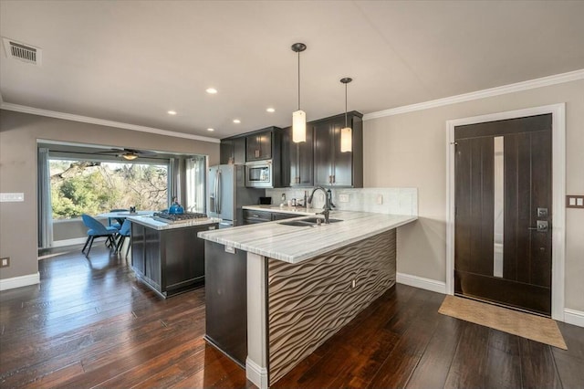 kitchen featuring sink, light stone counters, kitchen peninsula, pendant lighting, and stainless steel appliances