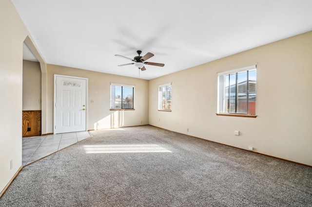 spare room featuring ceiling fan, light colored carpet, and a healthy amount of sunlight