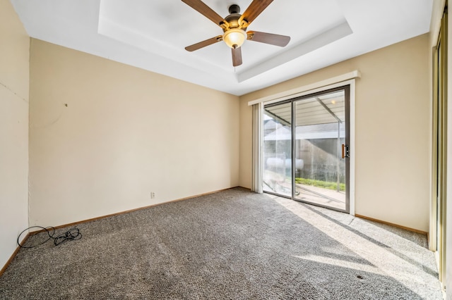 empty room featuring carpet flooring, ceiling fan, and a tray ceiling